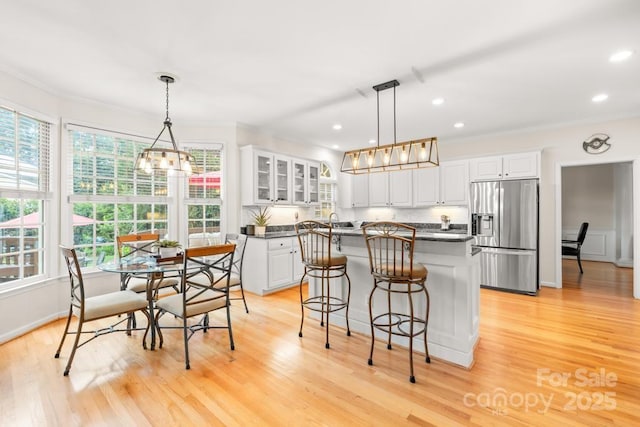 9514 Hayenridge Ct, Huntersville, NC 28078 - kitchen with stainless steel fridge with ice dispenser, dark countertops, crown molding, white cabinetry, and a kitchen island