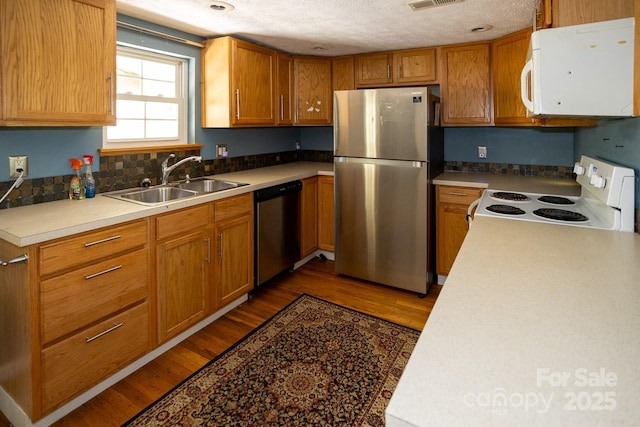 3153 US-70 Hwy E, Black Mountain, NC 28711 - kitchen featuring appliances with stainless steel finishes, dark wood-type flooring, a textured ceiling, brown cabinetry, and decorative backsplash