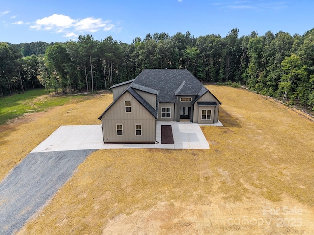 5507 NC-218 Hwy, Peachland, NC 28133 - view of front facade with board and batten siding, a forest view, a front yard, and a shingled roof