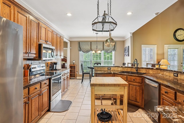 7612 Maple Bluff Ln, Concord, NC 28025 - kitchen with appliances with stainless steel finishes, light tile patterned floors, brown cabinets, pendant lighting, and ornamental molding