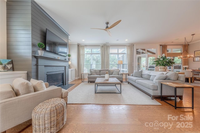 5256 Meadowcroft Way, Fort Mill, SC 29708 - living area featuring crown molding, light wood-type flooring, a ceiling fan, a fireplace with flush hearth, and a chandelier