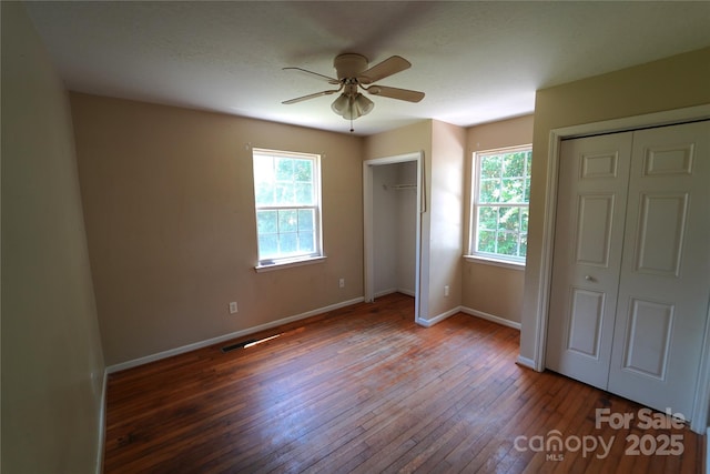 201 W 19th St, Kannapolis, NC 28081 - unfurnished bedroom featuring two closets, multiple windows, hardwood / wood-style floors, and ceiling fan