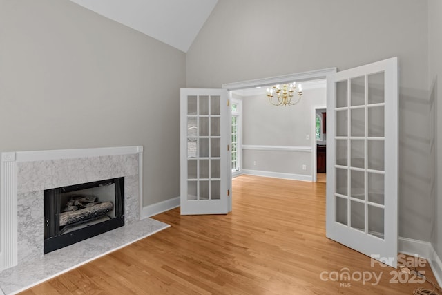 165 Futrell Lndg, New London, NC 28127 - unfurnished living room featuring high vaulted ceiling, wood finished floors, a fireplace, a chandelier, and french doors