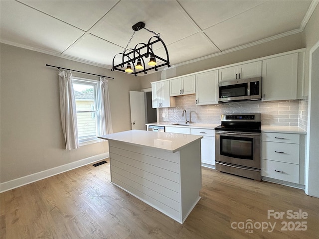 339 Mayflower Ave, Cramerton, NC 28032 - kitchen featuring appliances with stainless steel finishes, a chandelier, tasteful backsplash, ornamental molding, and white cabinetry