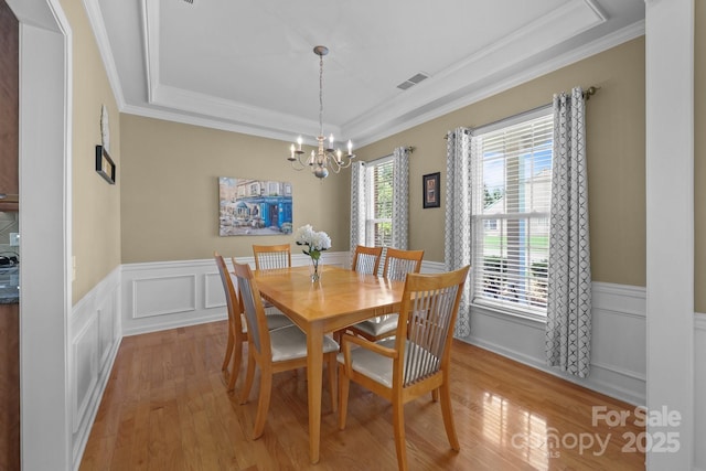 5238 Prosperity View Dr, Charlotte, NC 28269 - dining space with a tray ceiling, crown molding, a chandelier, light wood-style floors, and a wainscoted wall