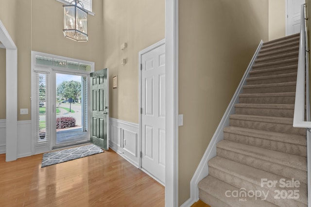 5238 Prosperity View Dr, Charlotte, NC 28269 - foyer featuring stairs, a chandelier, wood finished floors, a wainscoted wall, and a high ceiling