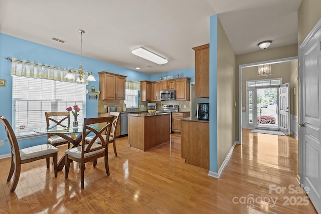 5238 Prosperity View Dr, Charlotte, NC 28269 - kitchen with appliances with stainless steel finishes, a chandelier, a center island, light wood-style flooring, and dark countertops