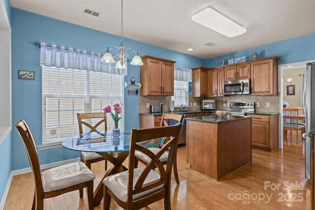 5238 Prosperity View Dr, Charlotte, NC 28269 - kitchen featuring stainless steel appliances, a chandelier, dark countertops, a kitchen island, and light wood-style flooring