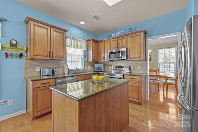 5238 Prosperity View Dr, Charlotte, NC 28269 - kitchen featuring appliances with stainless steel finishes, healthy amount of natural light, light wood-style flooring, dark stone counters, and recessed lighting
