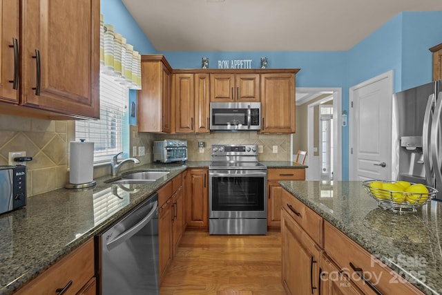 5238 Prosperity View Dr, Charlotte, NC 28269 - kitchen with appliances with stainless steel finishes, brown cabinets, light wood finished floors, dark stone counters, and decorative backsplash