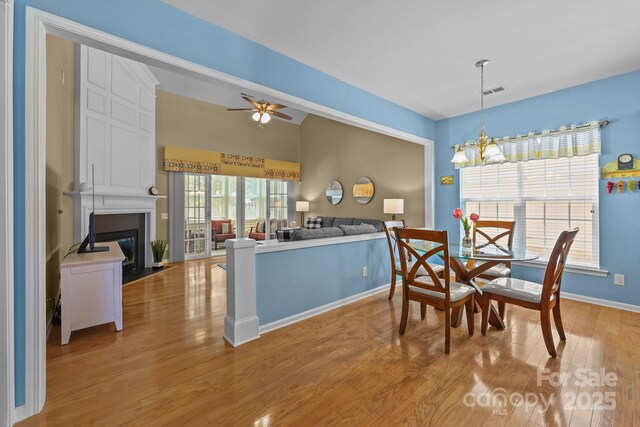 5238 Prosperity View Dr, Charlotte, NC 28269 - dining space with a chandelier, light wood finished floors, a fireplace, vaulted ceiling, and a ceiling fan