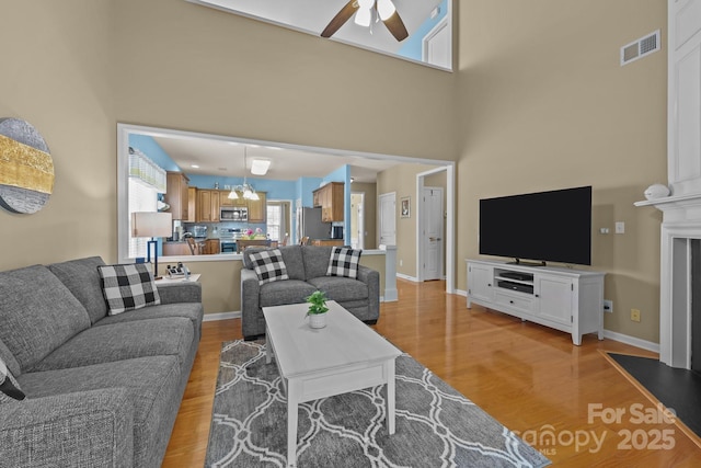 5238 Prosperity View Dr, Charlotte, NC 28269 - living room with a ceiling fan, light wood-style flooring, a high ceiling, and a chandelier