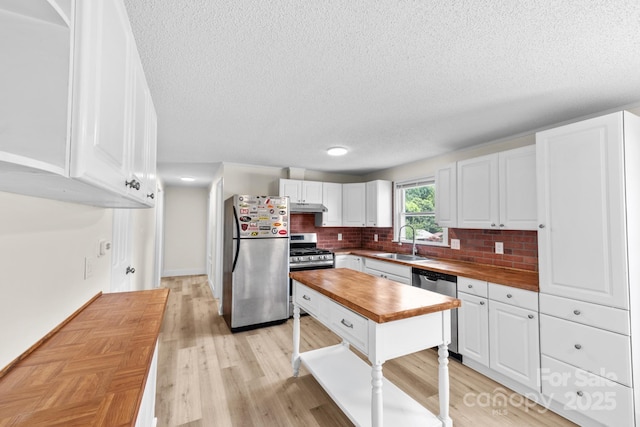 306 2nd Avenue Pl NE, Conover, NC 28613 - kitchen featuring wooden counters, stainless steel appliances, a textured ceiling, under cabinet range hood, and white cabinetry