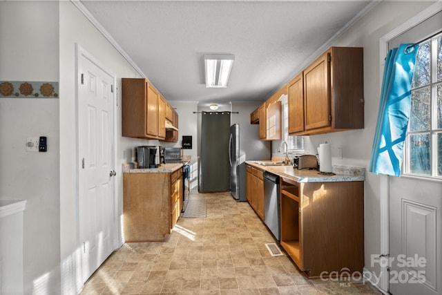 1013 Ashwood Pl, Salisbury, NC 28146 - kitchen featuring stainless steel appliances, light countertops, brown cabinetry, crown molding, and a textured ceiling