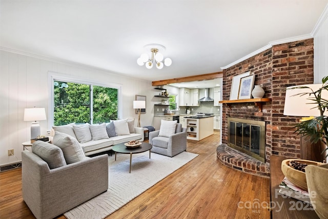 6150 Rocky Falls Rd, Charlotte, NC 28211 - living room featuring light wood finished floors, a brick fireplace, crown molding, and a chandelier