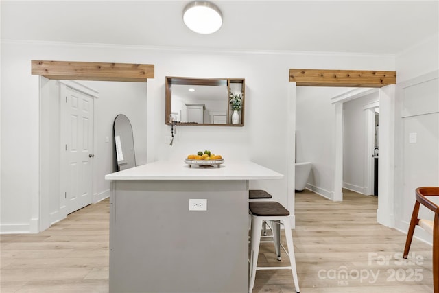 8438 Henry Harris Rd, Fort Mill, SC 29707 - kitchen featuring a kitchen breakfast bar, light wood-style flooring, crown molding, light countertops, and a peninsula
