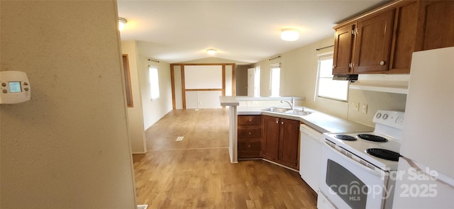 67 Brown Lynch Rd, Candler, NC 28715 - kitchen featuring white appliances, brown cabinetry, light wood-type flooring, lofted ceiling, and a peninsula
