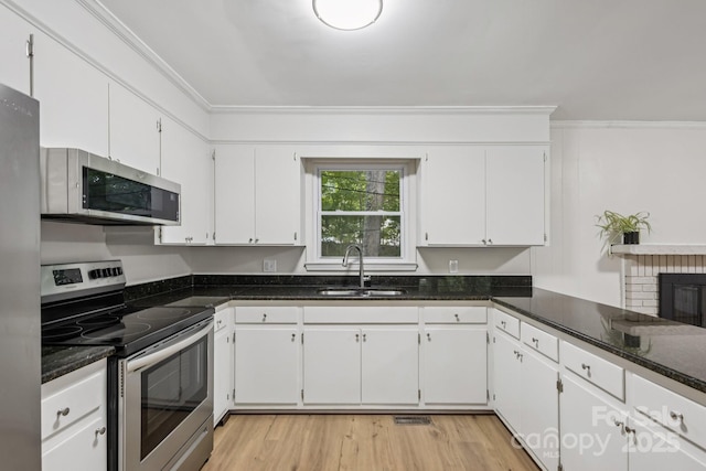 613 Davis St, Lancaster, SC 29720 - kitchen with appliances with stainless steel finishes, ornamental molding, white cabinetry, and light wood-style floors