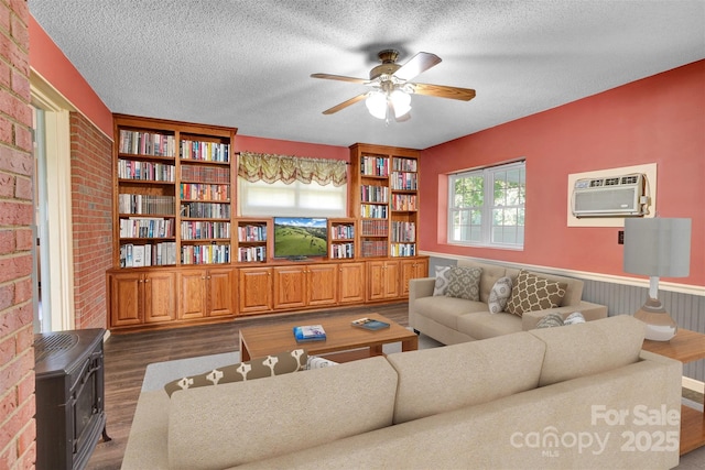 37156 Southside Rd, Albemarle, NC 28001 - living area with dark wood-style floors, a wood stove, a wall mounted AC, ceiling fan, and a textured ceiling