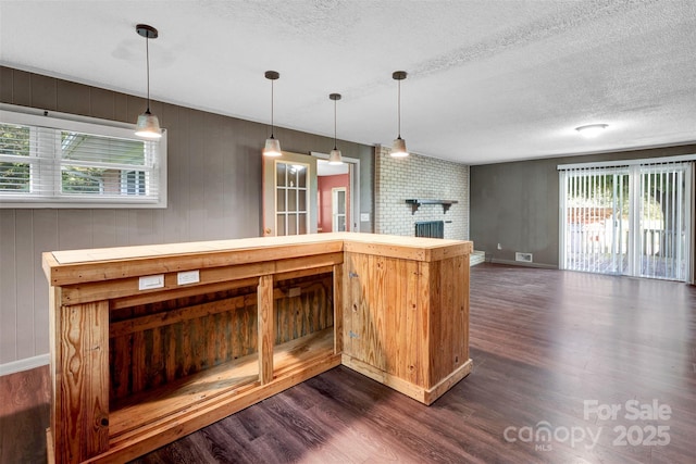 37156 Southside Rd, Albemarle, NC 28001 - kitchen featuring dark wood-type flooring, a textured ceiling, hanging light fixtures, open floor plan, and a brick fireplace
