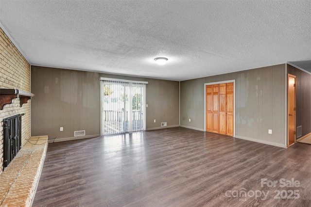 37156 Southside Rd, Albemarle, NC 28001 - unfurnished living room featuring dark wood-type flooring, a brick fireplace, a textured ceiling, and wood walls