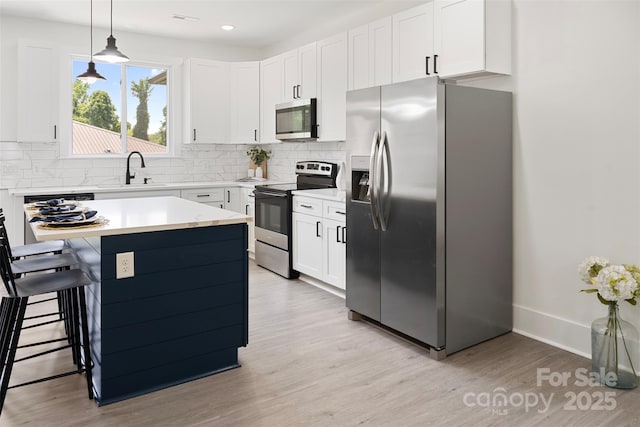103 Wadesborough Pl, Wadesboro, NC 28170 - kitchen with stainless steel appliances, light wood-style floors, decorative backsplash, a kitchen bar, and light countertops