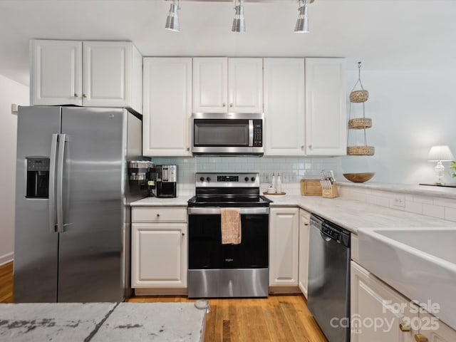 6934 Loretta Pl, Charlotte, NC 28215 - kitchen featuring appliances with stainless steel finishes, light wood-style floors, white cabinets, tasteful backsplash, and light stone countertops