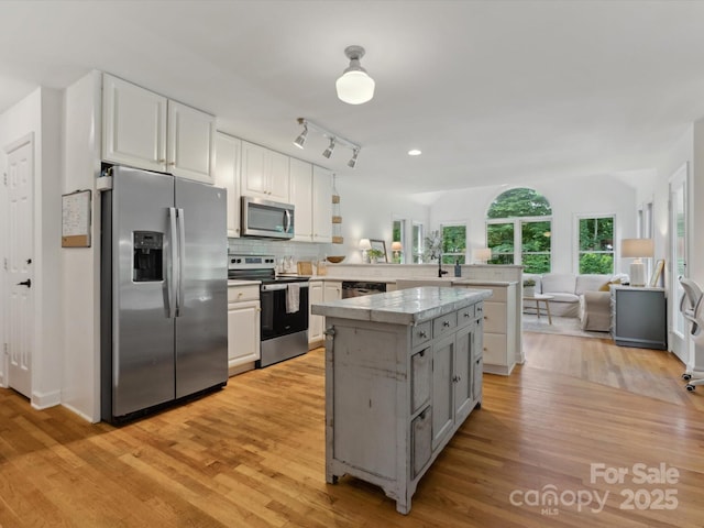6934 Loretta Pl, Charlotte, NC 28215 - kitchen with stainless steel appliances, a peninsula, light wood-type flooring, a kitchen island, and recessed lighting
