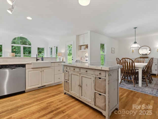 6934 Loretta Pl, Charlotte, NC 28215 - kitchen featuring stainless steel dishwasher, light countertops, light wood-style flooring, white cabinets, and recessed lighting