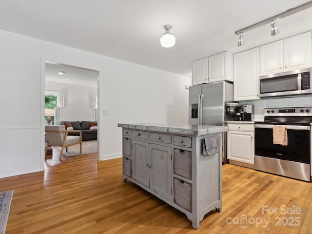 6934 Loretta Pl, Charlotte, NC 28215 - kitchen featuring appliances with stainless steel finishes, light wood-style flooring, white cabinetry, and wainscoting
