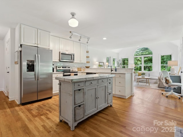 6934 Loretta Pl, Charlotte, NC 28215 - kitchen featuring appliances with stainless steel finishes, a peninsula, gray cabinets, light countertops, and light wood-type flooring