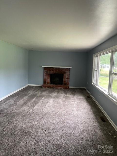 unfurnished living room featuring dark colored carpet and a brick fireplace