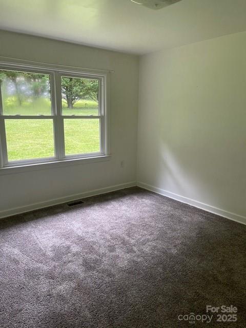 spare room featuring carpet flooring and baseboards