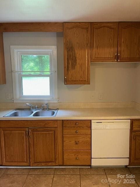 kitchen featuring white dishwasher, light countertops, light tile patterned flooring, and brown cabinets