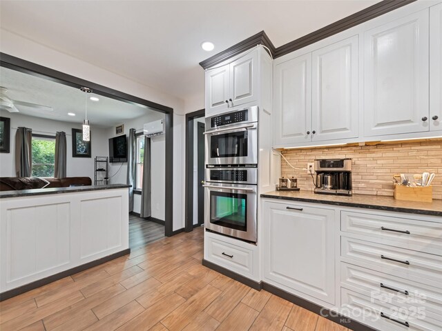 229 Yellow Bird Branch Rd, Sylva, NC 28779 - kitchen with double oven, an AC wall unit, decorative backsplash, white cabinetry, and light wood-style floors