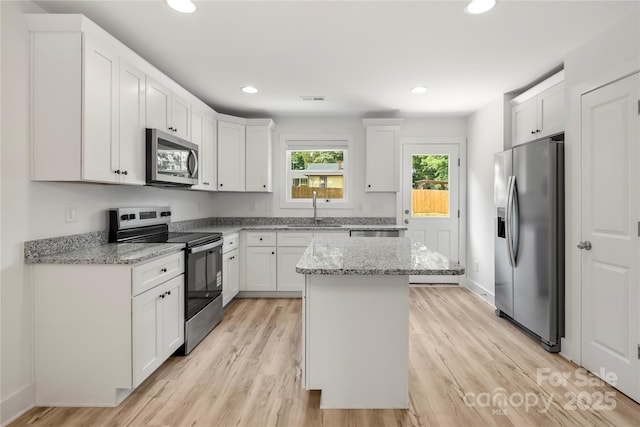 443 Faith Dr SW, Concord, NC 28027 - kitchen featuring stainless steel appliances, white cabinets, light wood finished floors, a center island, and recessed lighting