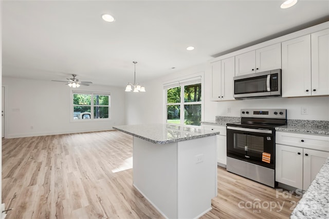 445 Faith Dr SW, Concord, NC 28027 - kitchen featuring stainless steel appliances, light wood-type flooring, open floor plan, white cabinets, and a chandelier