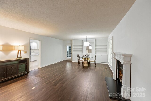55 Diamond Ridge Ln, Columbus, NC 28722 - living room with dark wood finished floors, built in shelves, a textured ceiling, and a lit fireplace