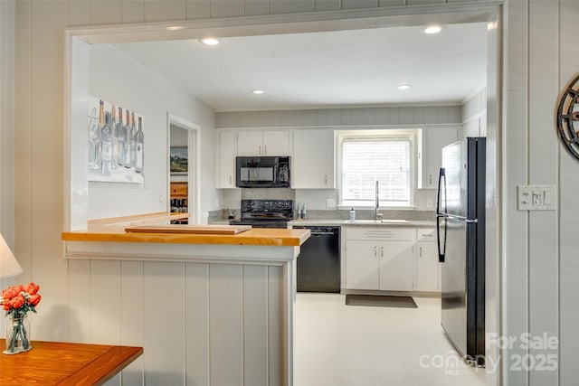 7026 Tabor Ln, Charlotte, NC 28211 - kitchen with black appliances, white cabinets, butcher block counters, a peninsula, and recessed lighting