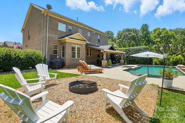 7903 Tottenham Ct, Waxhaw, NC 28173 - rear view of house with an outdoor fire pit, a patio area, brick siding, and a pool with connected hot tub