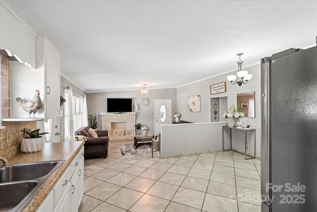1627 33rd Ave NE, Hickory, NC 28601 - kitchen with freestanding refrigerator, ornamental molding, a brick fireplace, white cabinets, and open floor plan