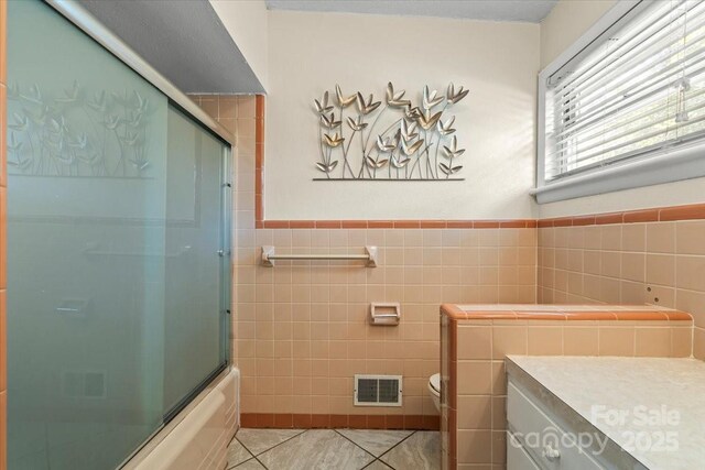 1627 33rd Ave NE, Hickory, NC 28601 - bathroom featuring tile walls, tile patterned floors, enclosed tub / shower combo, a wainscoted wall, and vanity
