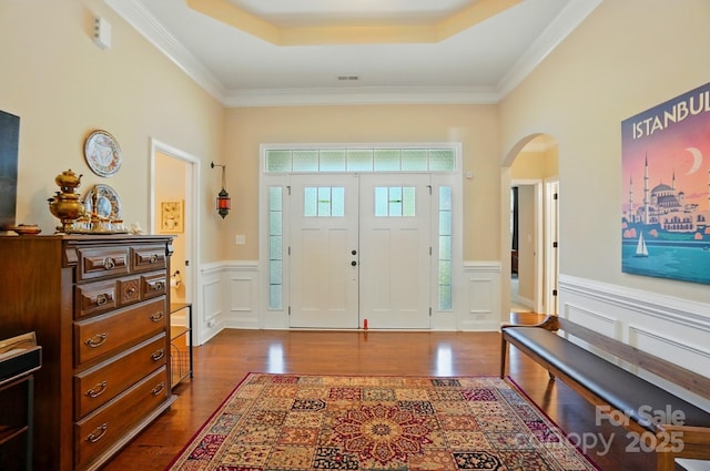9330 Carneros Creek Rd, Charlotte, NC 28214 - foyer entrance with a wainscoted wall, dark wood-style floors, arched walkways, a decorative wall, and a tray ceiling