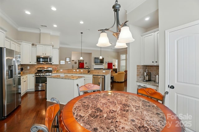 9330 Carneros Creek Rd, Charlotte, NC 28214 - kitchen with appliances with stainless steel finishes, a center island, crown molding, backsplash, and dark wood finished floors