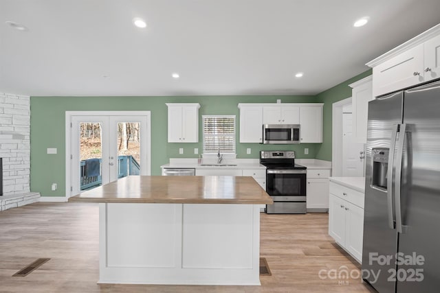 3433 Spinner Ct, Sherrills Ford, NC 28673 - kitchen with appliances with stainless steel finishes, french doors, white cabinets, a center island, and light wood-style floors
