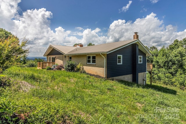 41 Remembrance Rdg, Flat Rock, NC 28731 - back of house with a chimney, brick siding, a metal roof, and a deck