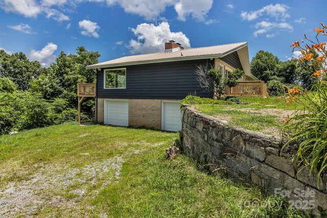 41 Remembrance Rdg, Flat Rock, NC 28731 - view of side of home with an attached garage, a chimney, a wooden deck, a metal roof, and a lawn
