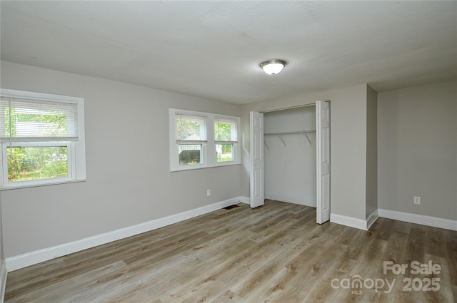 636 Forest St NW, Concord, NC 28025 - unfurnished bedroom with multiple windows, wood finished floors, and a closet