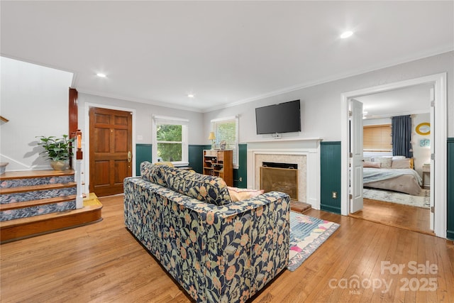 2034 Lanier Ave, Charlotte, NC 28205 - living area featuring light wood finished floors, crown molding, a fireplace with raised hearth, stairs, and recessed lighting