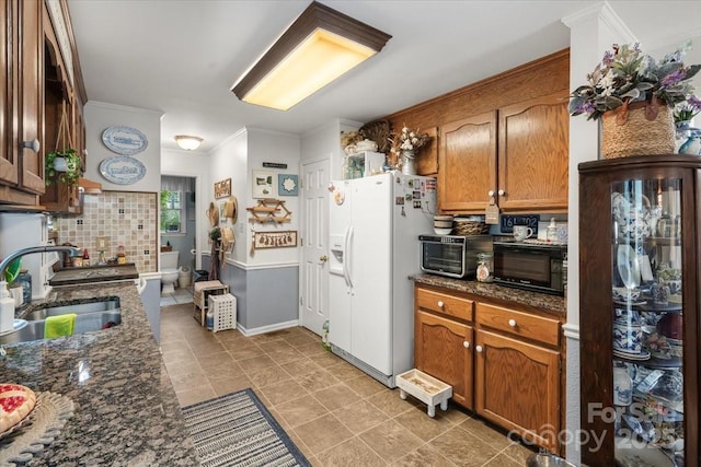 111 Beacon Hills Dr, Gastonia, NC 28056 - kitchen with white refrigerator with ice dispenser, ornamental molding, brown cabinetry, backsplash, and dark stone countertops